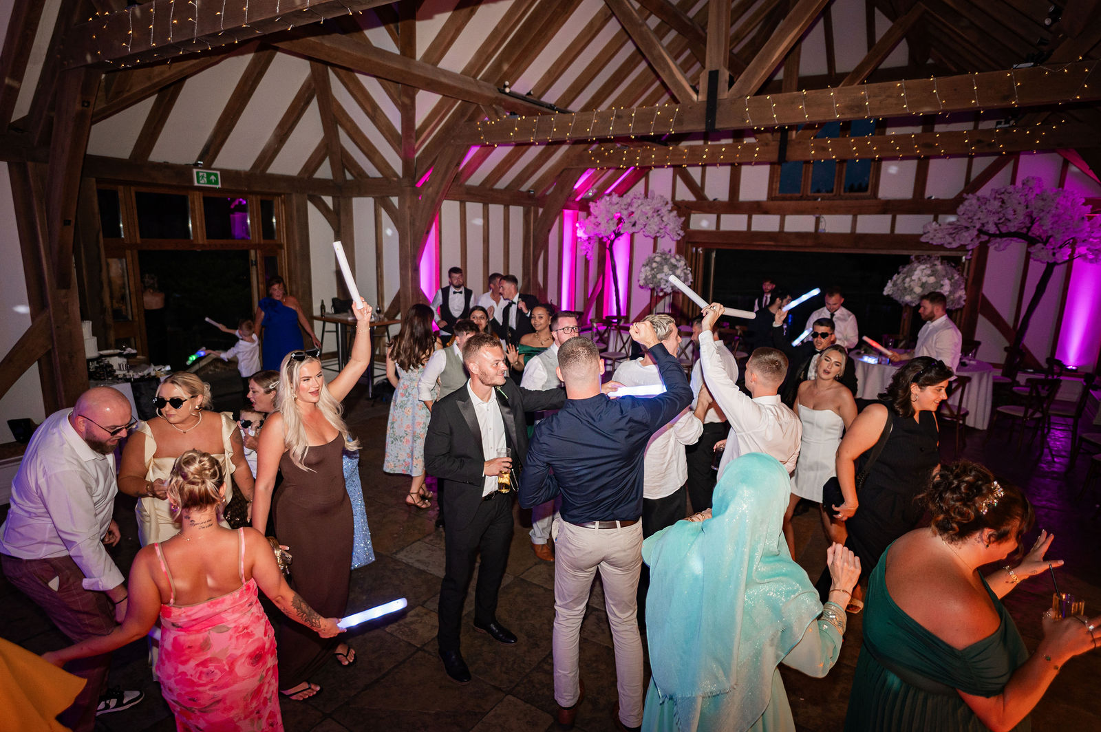 Wedding guests and the couple celebrating together on a busy evening dance floor